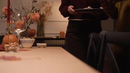 Handheld shot of two diverse girlfriends talking while setting table with cutlery for Thanksgiving celebration at home - Powered by Adobe