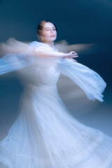 Naklejka premium Expressive dancer in white gown, arms extended through luminous motion blur. Concept of high-end fragrance, decor identity, and emotional mindfulness through dynamic elegance.