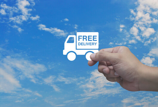 Hand holding free delivery truck flat icon in fingers over blue sky with white clouds, Business transportation service concept