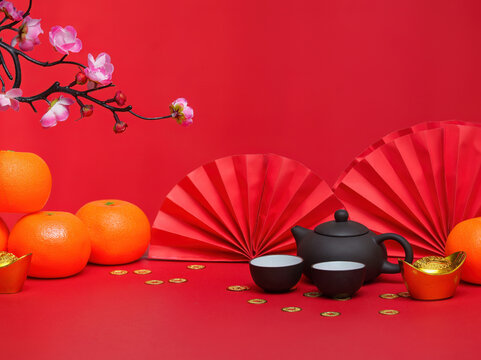 Chinese New Year Tea Ceremony. Teapot and cups with oranges on a vibrant red background. - Powered by Adobe