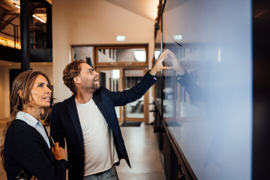 Business team discussing innovation at big screen in modern office