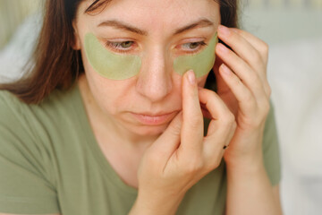 40s woman takes self facial care at morning. She applying a serum from glass dropper to her face skin. Skincare product. Female applies essential oil with oily pipette. Advertising cosmetics. Health.
