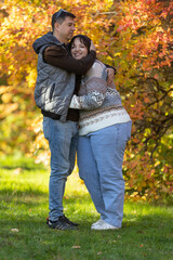 Fototapeta premium A young couple in love walks through the park with their pet. The lovers enjoy the golden autumn scenery.