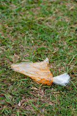 Plastic food waste is thrown carelessly on grass in the park