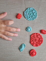Covid and other respiratory virus molecules made of plasticine. Little toddler education moment in a playful mode. Bacteria made of playdough and kids' hands over the table. 