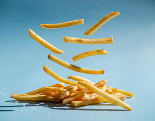 Golden French Fries Floating in Air on Pastel Blue Background