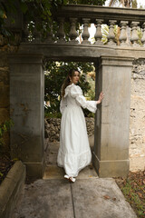 Fototapeta premium Full length female figure of beautiful blonde model wearing white fantasy wedding gown. walking through doorway of historical fairytale castle location 