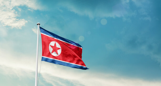 North Korea national flag fluttering. The flag blowing in beautiful soft sky. Korea national flag for independence day. - Powered by Adobe
