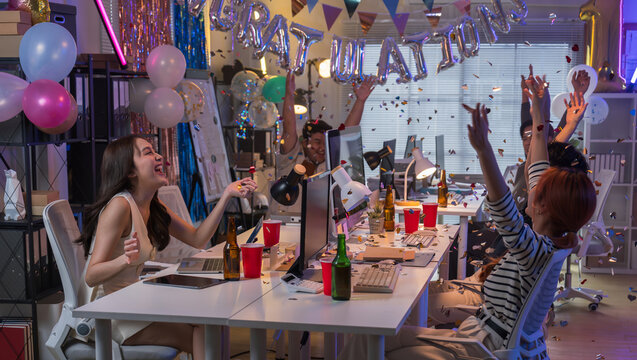 Young Asian coworkers excitedly celebrate business success in a modern office, cheering and congratulating each other with confetti, smiles, and high energy after achieving extraordinary growth.