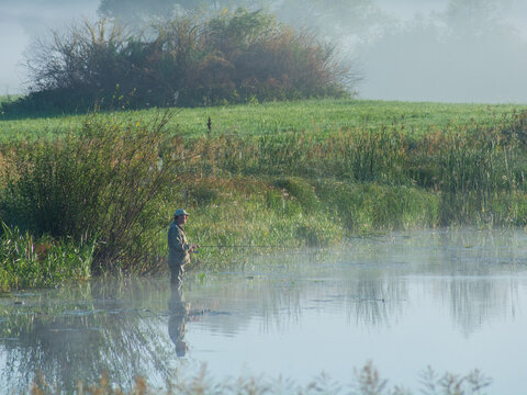 Fishing on the swamp at sunrise with mist over water
