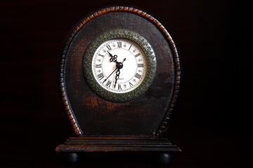 Wooden brown clock on dark background