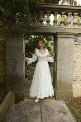 Obraz premium Full length female figure of beautiful blonde model wearing white fantasy wedding gown. walking through doorway of historical fairytale castle location 
