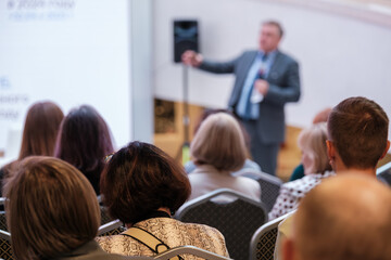 Speaker presents to attentive audience in conference room delivering key insights, professional...