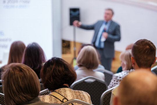 Speaker presents to attentive audience in conference room delivering key insights, professional event focused on learning and networking, improving communication and collaboration.