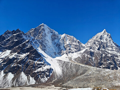 Snow-covered mountains tower under a bright blue sky showcasing natural beauty and grandeur. Himalayan Mountains, Nepal. Everest base camp - Powered by Adobe