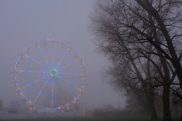 Riesenrad im Nebel neben B&auml;umen im Park