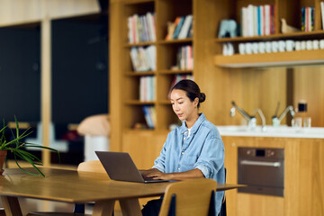 Asian Woman Working on Laptop at Modern Home Office Kitchen Island and Library