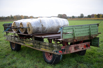 Trecker-Anh&auml;nger auf einer Ackerbaufl&auml;che der Landwirtschaft einer Herbstlandschaft im faden, nat&uuml;rlichen Morgenlicht.