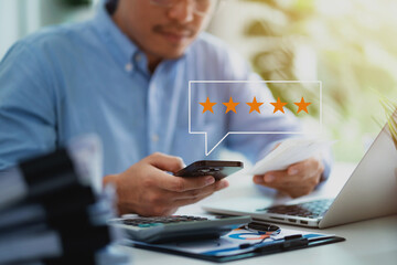 A man is sitting at a desk with a laptop and a cell phone