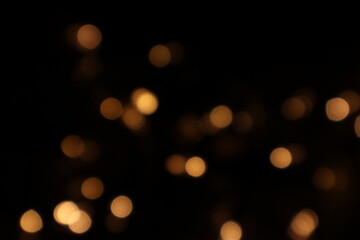 Golden blurred bokeh lights on black background. Glitter sparkle stars for celebrate. Overlay for your design. Bokeh effect golden light background. Golden Christmas concept. yellow sparkling bokeh