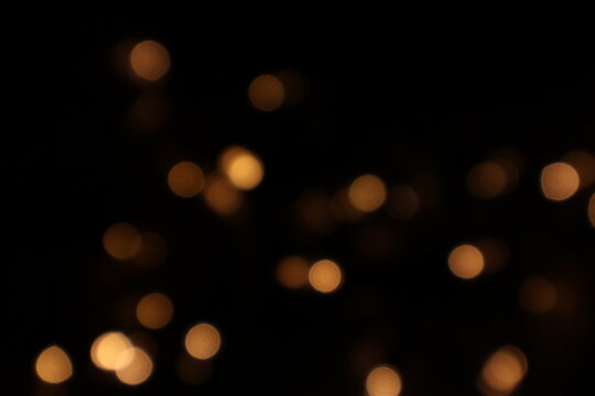 Golden blurred bokeh lights on black background. Glitter sparkle stars for celebrate. Overlay for your design. Bokeh effect golden light background. Golden Christmas concept. yellow sparkling bokeh - Powered by Adobe