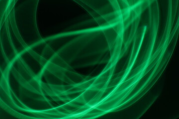 Abstract green light trails on dark background, long-exposure swirling motion lines for technology and energy background. Abstract green smoke or green fire on dark background. Green gas fire abstract