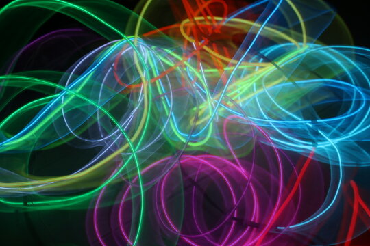 Colorful Neon Light Loops on Dark Background – Abstract Glowing Circles, Red Green Yellow Blue Light Trails, Futuristic Vivid Motion Blur Texture - Powered by Adobe