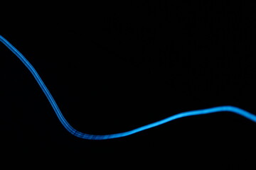 Abstract blue light trails on dark background, long-exposure swirling motion lines for technology...