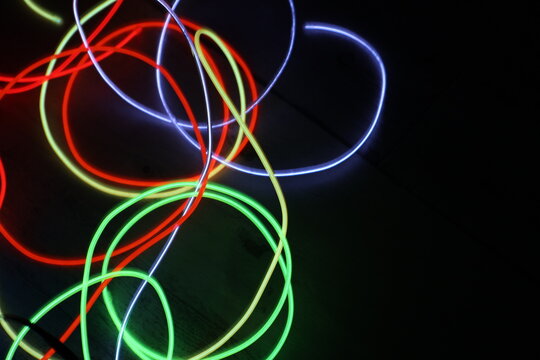 Colorful Neon Light Loops on Dark Background – Abstract Glowing Circles, Red Green Yellow Blue Light Trails, Futuristic Vivid Motion Blur Texture