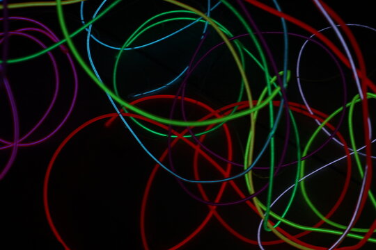 Colorful Neon Light Loops on Dark Background – Abstract Glowing Circles, Red Green Yellow Blue Light Trails, Futuristic Vivid Motion Blur Texture