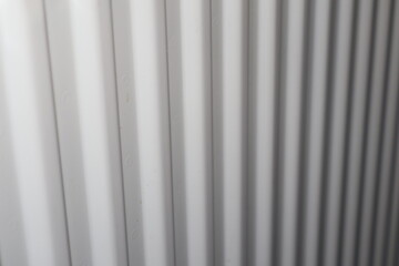 Obraz premium White radiator heating panel with vertical fins, close-up of indoor heating element in home interior