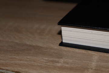 Close-up hardcover book on wooden table, pages and cover detail in shallow depth of field for reading, study and knowledge concept