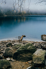 Misty Mountain Lake with Autumn Forest Reflections and Rocky Shore in Fall