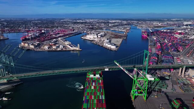 Aerial view of the Vincent Thomas Bridge with a cargo ship passing underneath and containers at the port, Los Angeles, California, United States.