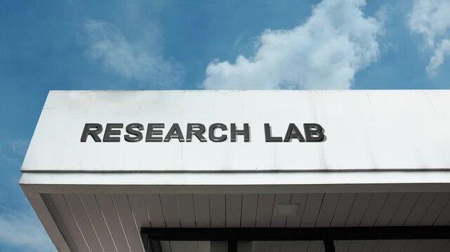 A Research Lab word sign displayed on a modern academic or corporate building under a clear blue sky, symbolizing scientific experimentation, technology, innovation, discovery, and testing