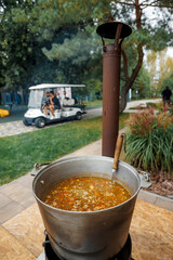 The ukha is being cooked in a large cauldron.