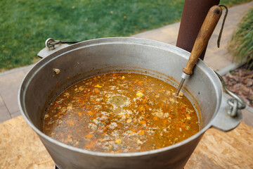 The ukha is being cooked in a large cauldron.