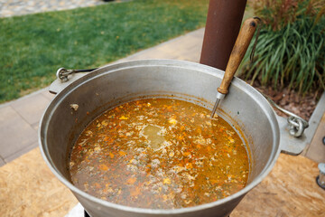 The ukha is being cooked in a large cauldron.