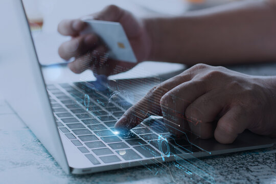Close-up of hands making secure online payment using credit card and laptop with digital data overlay representing modern financial technology.