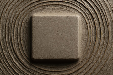 Stone placed on a smooth, circular pattern of sand reflecting tranquility and simplicity in a Zen garden setting