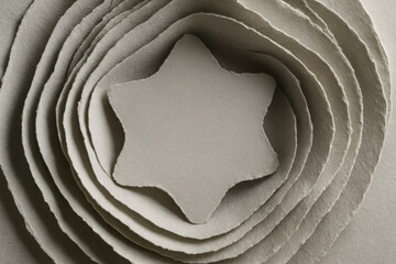 Intricate layers of cut paper arranged in a circular pattern with a star shape at the center