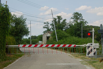 Rural railway crossing with barrier and red signal light — transport safety and countryside travel concept