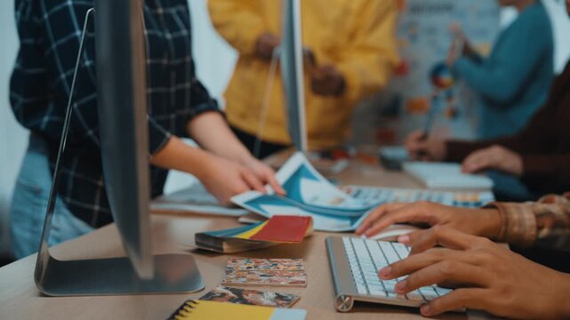 A vibrant office scene showcasing professionals engaged in teamwork, surrounded by colorful design materials and modern technology, emphasizing creativity and collaboration. SACTR