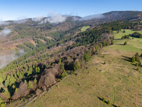 Aerial view of rolling hills painted with verdant meadows and dense forests under a cerulean sky, a serene landscape of Slovakia's countryside., Hrinova, Banskobystricky kraj, Slovakia.