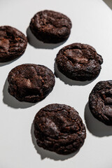 A neatly arranged set of six rich, dark chocolate cookies placed in a grid formation on a clean white surface. The cookies appear moist, dense, and fudgy, suggesting a deep cocoa flavor