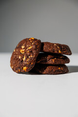 A stack of rich double chocolate cookies with nut chunks arranged on a white surface, showcasing texture and contrast. No visible branding