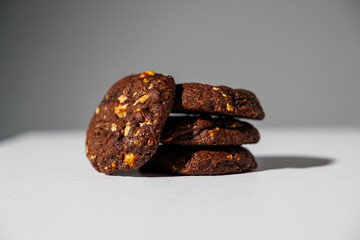 A stack of rich double chocolate cookies with nut chunks arranged on a white surface, showcasing texture and contrast. No visible branding