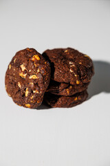 A stack of rich double chocolate cookies with nut chunks arranged on a white surface, showcasing texture and contrast. No visible branding