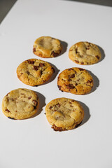 A set of six golden-brown chocolate chip cookies arranged in two neat columns on a clean white surface. No visible logos or branding