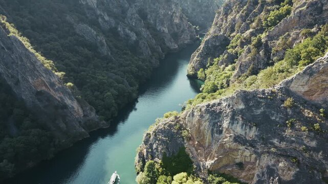 Stunning drone view of Matka Canyon near Skopje, a ship is sailing the river, 4k